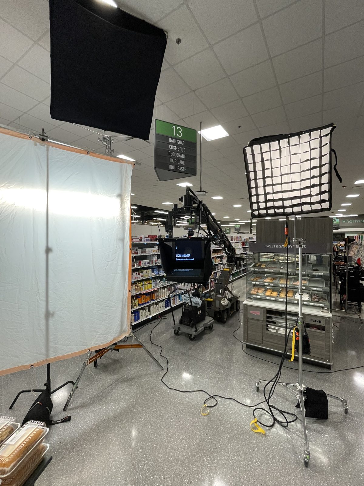 Camera jib with teleprompter, diffusion frame and softbox lighting on an in-store commercial set
